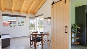 A modern interior with a wooden ceiling, a sliding door, a dining area with chairs, and a view through the door. - Apartamentos aronces  (Cudillero)