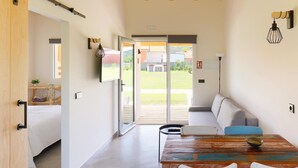A modern interior with a dining area, a sofa, and a sliding glass door leading to a balcony. - Apartamentos aronces  (Cudillero)