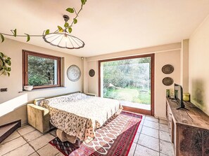 Un dormitorio con cama, ventana, puerta y vistas al exterior.