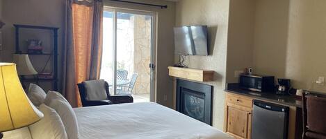 Una habitación de hotel con una cama, un escritorio con microondas, televisor y chimenea.