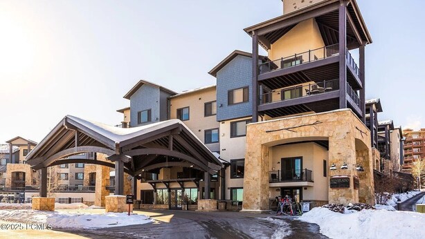 Een meerhoog hotel met een opvallende klok op het bovenste niveau, een gevel van natuursteen en ski-uitrusting buiten.