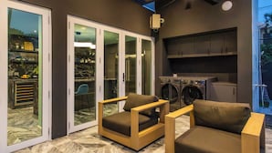 Een moderne keuken met een ingebouwde wasmachine, een schuifdeur naar een patio met twee houten stoelen en een tafel.