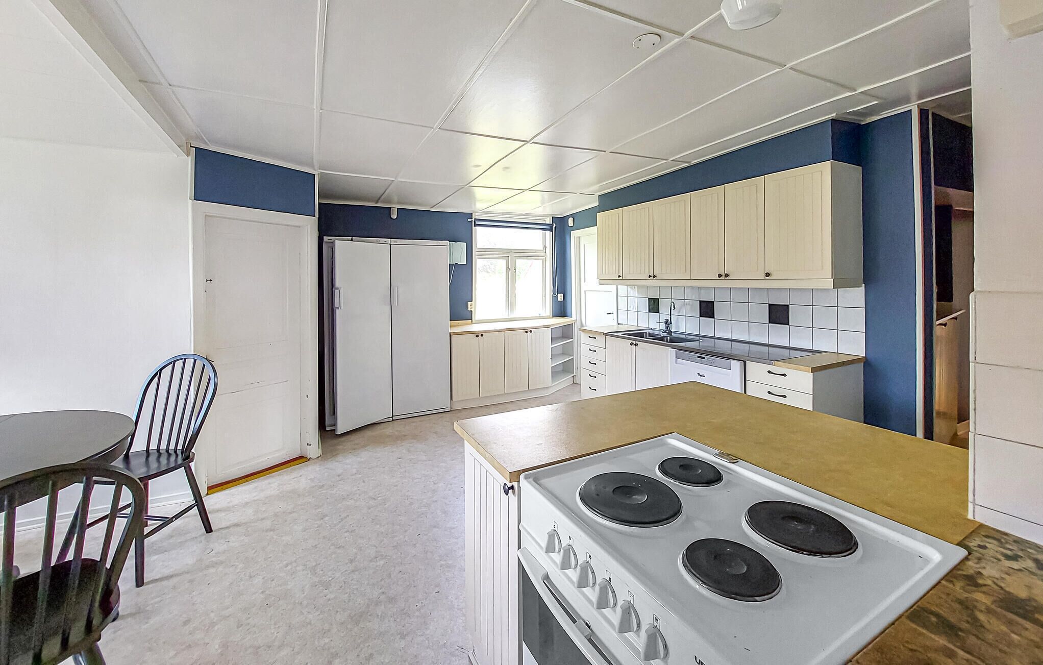 Een keuken met een fornuis, kastjes en een raam.