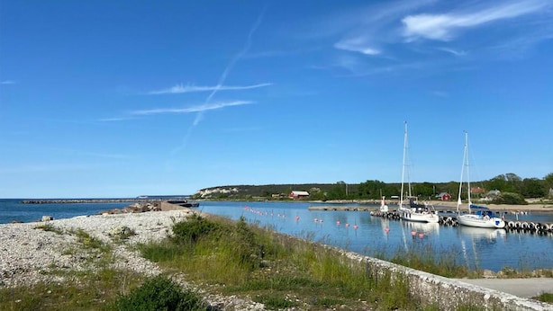 Um porto tranquilo com barcos atracados, céu claro e costa rochosa.
