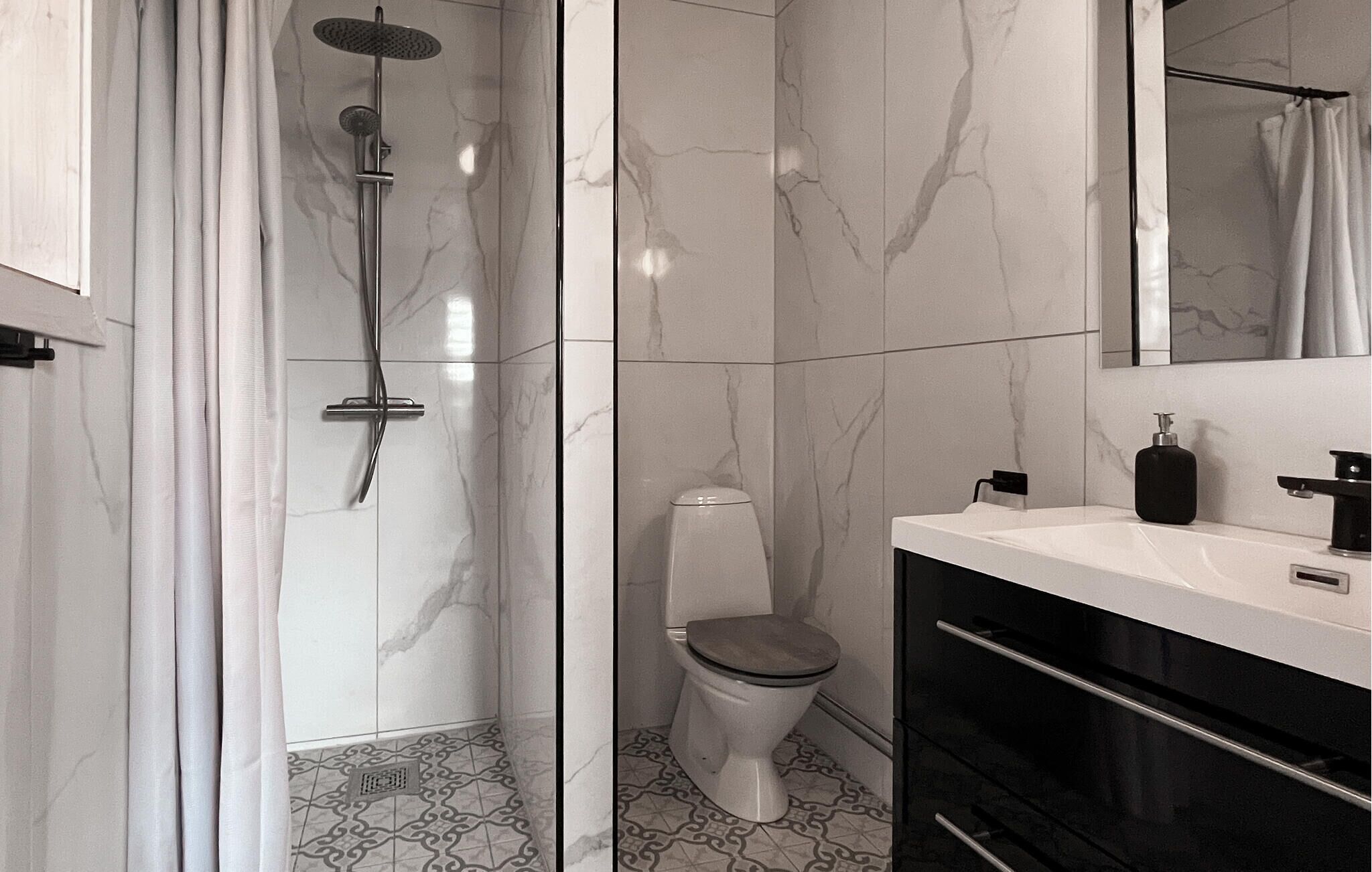 A modern bathroom with a shower, toilet, and sink.