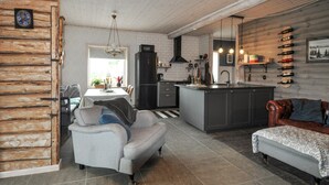 Una cocina moderna con una isla central, un comedor con sofá y una sala de estar con sofá.
