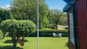 Un jardin bien entretenu, avec un hamac, une pelouse et un bâtiment à l’extérieur rouge.
