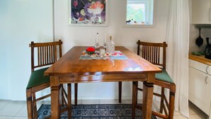 Une table à manger en bois, des chaises, un tapis et un tableau accroché au mur.