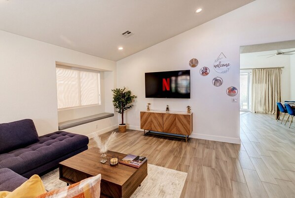 Un salon moderne avec un canapé, une table basse et un téléviseur fixé au mur.