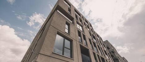A modern building with a geometric facade, multiple windows, and a clear sky.