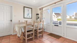 A dining area with a table and chairs, a framed picture on the wall, and a sliding glass door leading to a balcony.