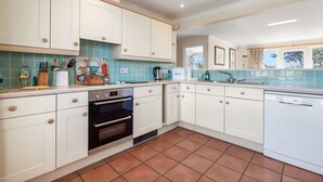 A kitchen with white cabinets, a tiled backsplash, a built-in oven, and a dishwasher.