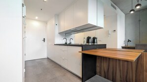 Une cuisine moderne avec des meubles blancs, un plan de travail en bois et un revêtement mural noir.