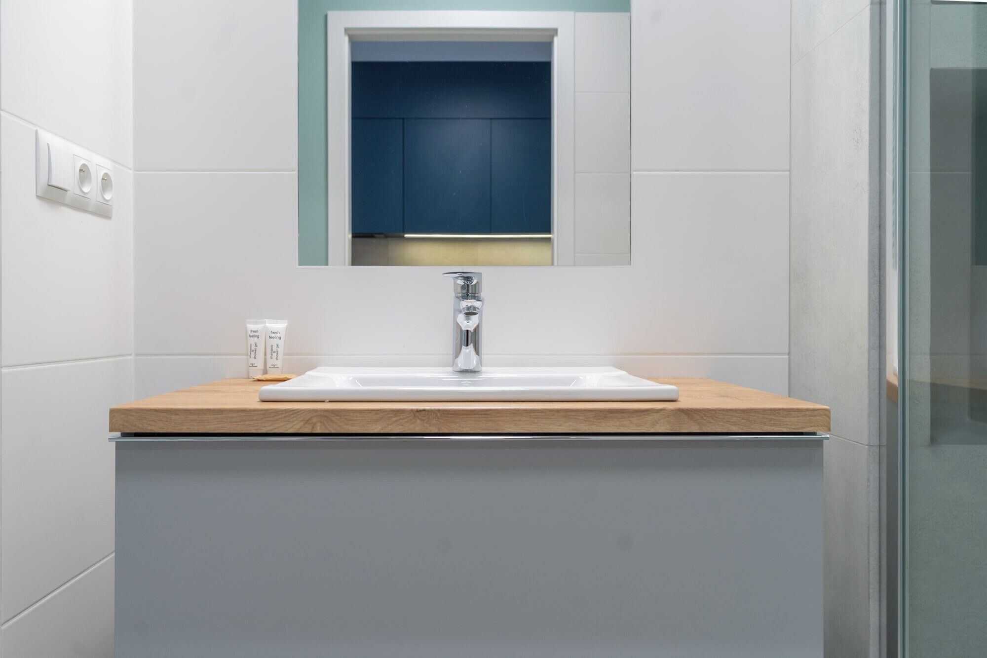 A bathroom with a white sink, a mirror, and a wooden countertop.