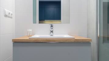 A bathroom with a white sink, a mirror, and a wooden countertop.