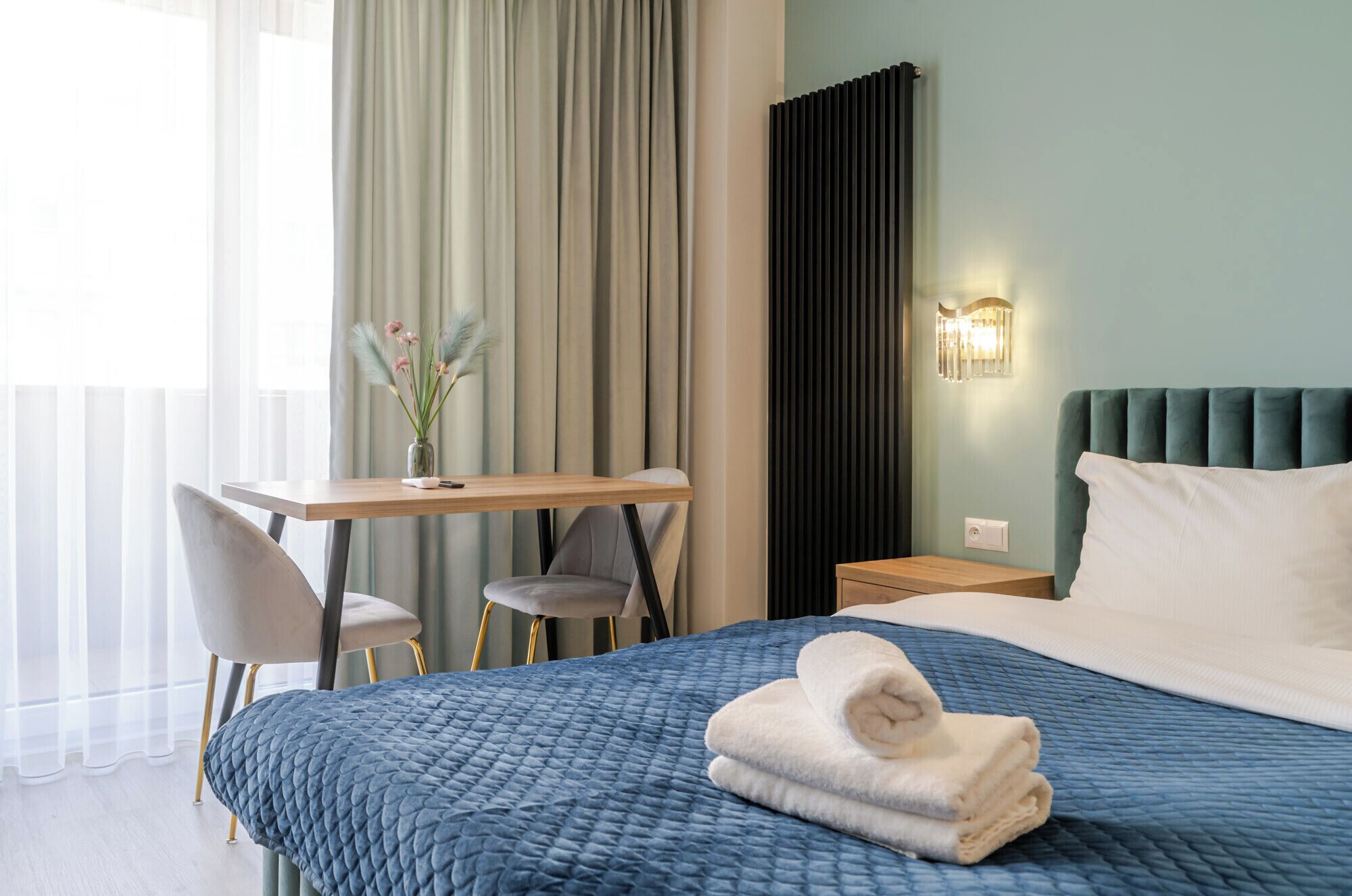 A hotel room with a bed, a desk, a chair, and a nightstand.