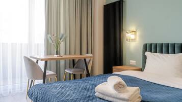 A hotel room with a bed, a desk, a chair, and a nightstand.