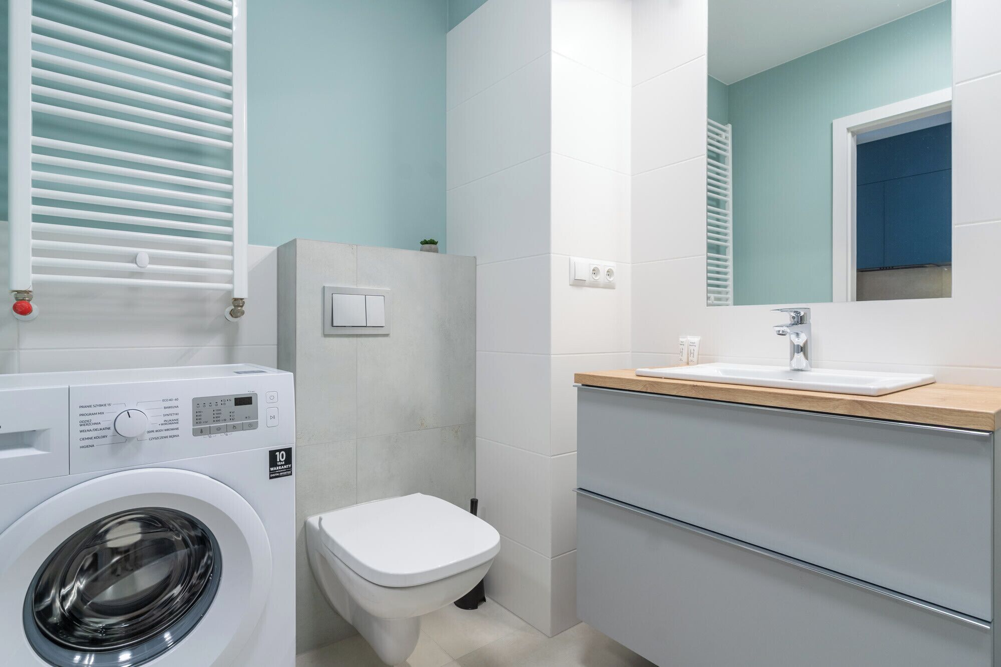 Ein kleines Badezimmer mit Waschmaschine, Toilette und Waschbecken.