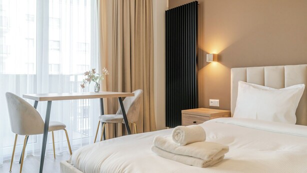 Ein Hotelzimmer mit einem Bett, einem Schreibtisch, einem Sessel und einem Nachttisch.