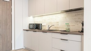 A modern kitchen with white cabinets, a wooden countertop, a built-in microwave, and a stainless steel faucet. - Business Deluxe Studio 48 (Katowice)