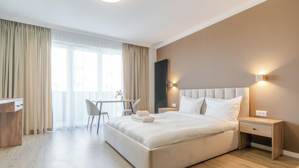 A modern hotel room with a large bed, bedside tables, a desk, and a chair. - Business Deluxe Studio 48 (Katowice)