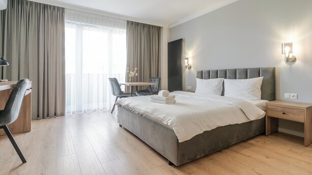 A modern hotel room with a large bed, a desk, and a chair. - Business Deluxe Studio 38 (Katowice)