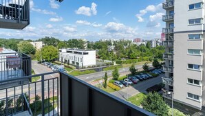 A view from a balcony overlooking a parking lot and a modern building with multiple floors and balconies. - Business Deluxe Studio 38 (Katowice)