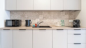 A kitchen with a microwave, coffee maker, and water bottles on the counter. - Business Deluxe Studio 38 (Katowice)