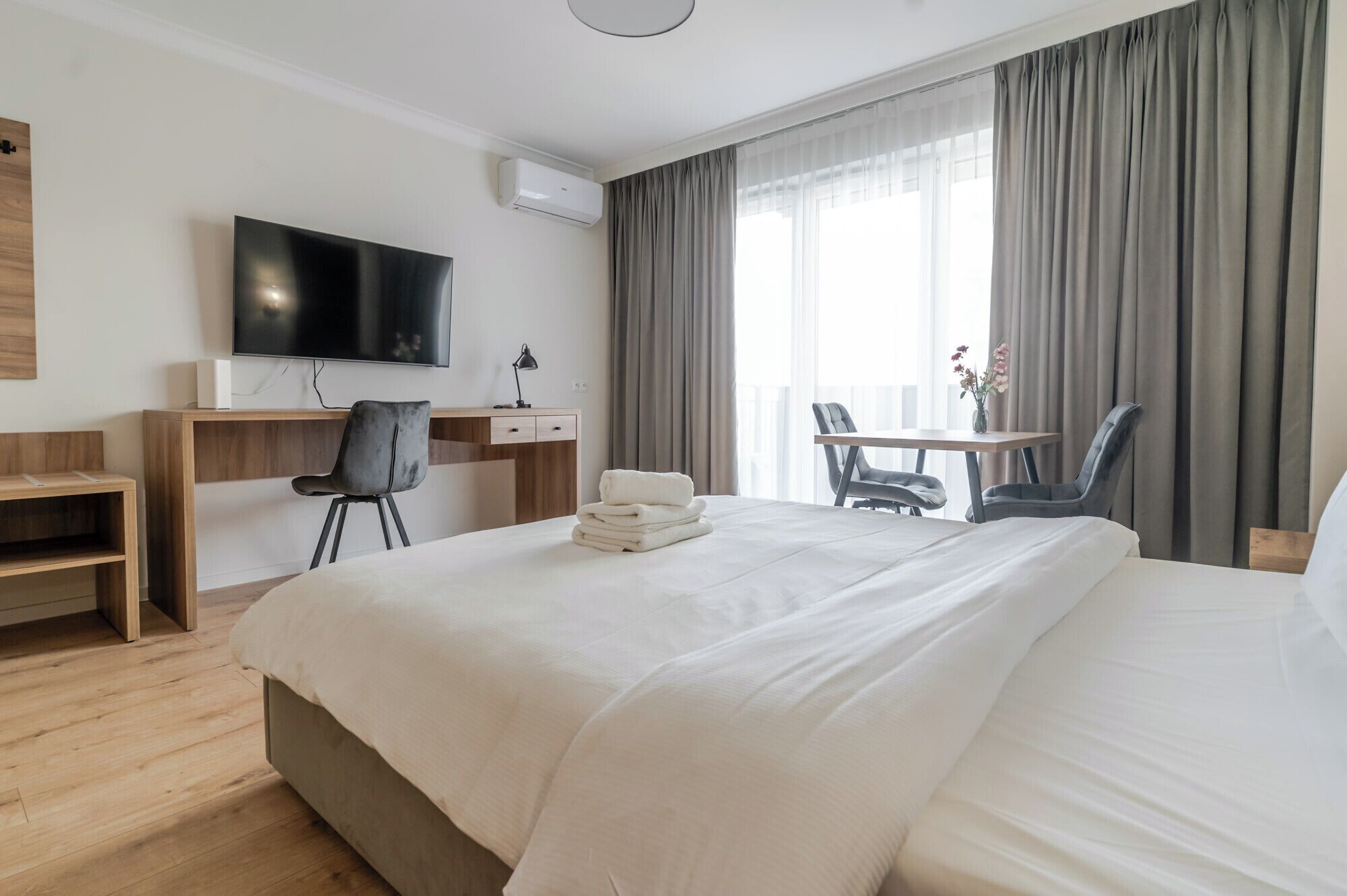 Una camera d'albergo con un letto, una scrivania con una sedia, una televisione e una finestra con tende.