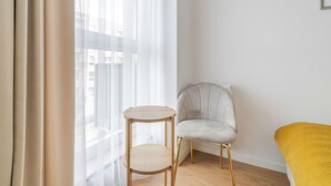 A corner room with a round wooden table, a grey upholstered chair, and a yellow chair. - Business Deluxe Studio 19 (Katowice)
