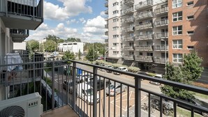 Un immeuble résidentiel doté de nombreux balcons, un espace de stationnement avec des voitures et une vue sur la rue.