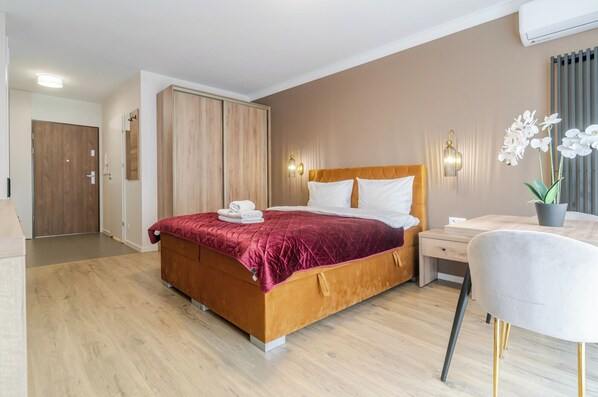 Una habitación de hotel con cama, escritorio, silla y una planta en maceta.