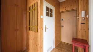 A room with wooden walls, a white door with a window, a red table, and a telephone on the wall.