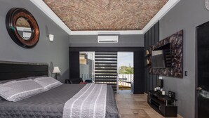 A modern bedroom with a large bed, a TV mounted on the wall, and a balcony with a view.