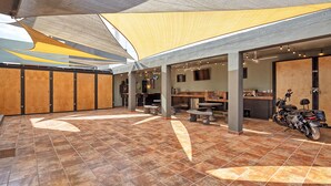 A spacious indoor area with a tiled floor, a motorcycle, and a seating area with tables and chairs.
