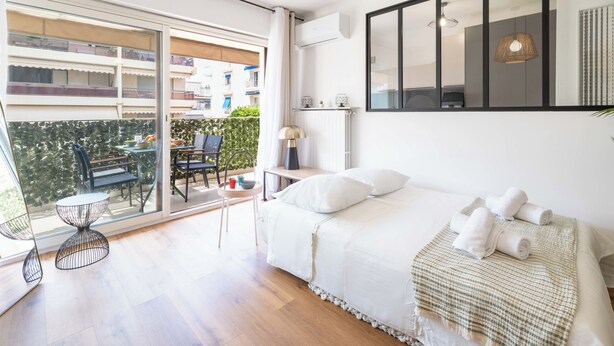 A modern bedroom with a large bed, a balcony with a table and chairs, and a large window. - 1-Br with Terrace – Palm Beach, Close to Beaches (Cannes)