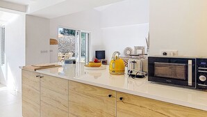 Une cuisine moderne dotée d’un grand îlot central, d’un grille-pain et d’une bouilloire.