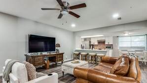 Una sala moderna con un sofá de cuero, un televisor y un ventilador de techo.