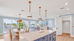 Una cocina moderna con una isla grande, iluminación colgante y vistas al exterior.