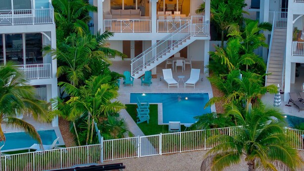 A multi-story hotel with a pool area surrounded by palm trees.
