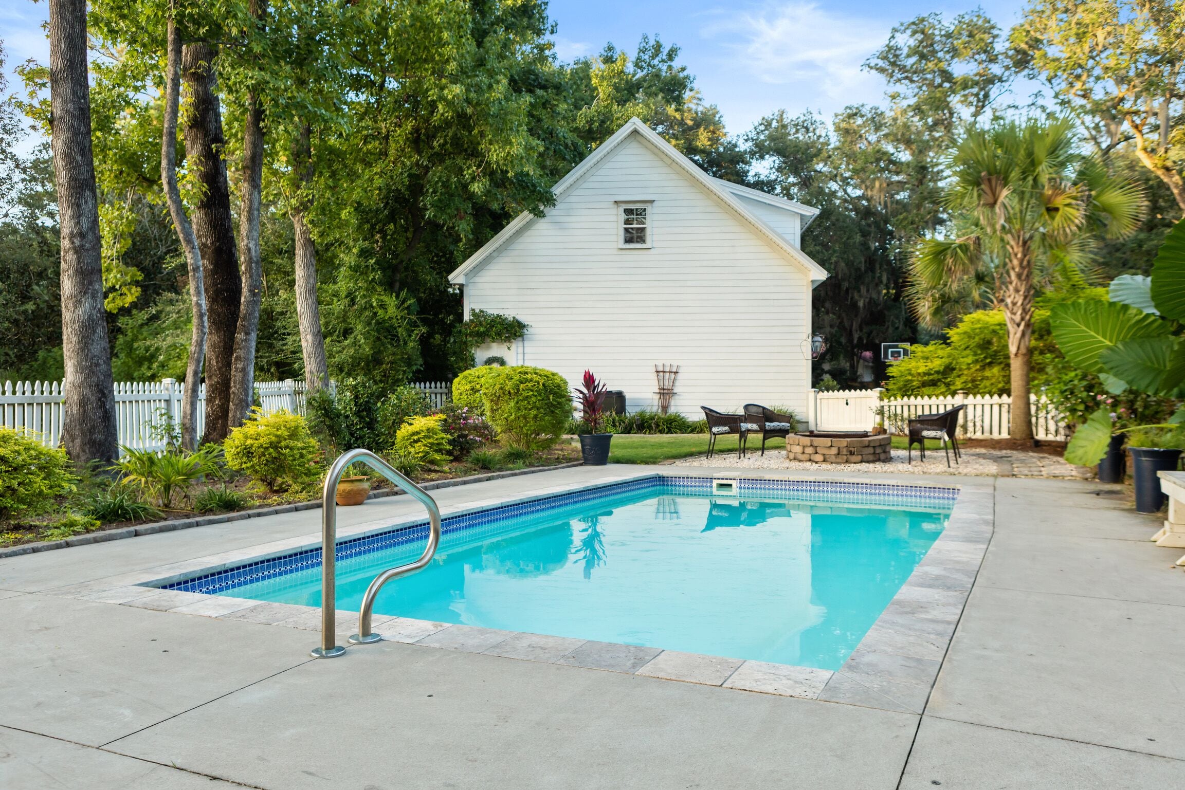 A rectangular swimming pool with a tiled edge, surrounded by a concrete deck.