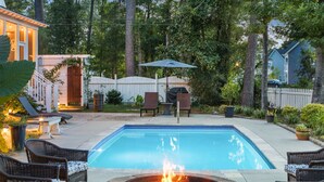 A backyard with a swimming pool, outdoor seating, and a fire pit.