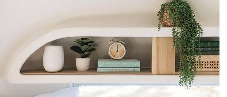 A shelf with a potted plant, a book titled 'The Smart Walk Strong', and a vintage alarm clock.