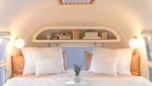 A bedroom with a large bed, a skylight, and built-in shelves above the bed.
