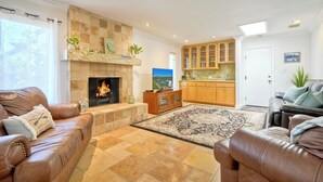A living room with a fireplace, leather sofas, a rug, and wooden cabinets.