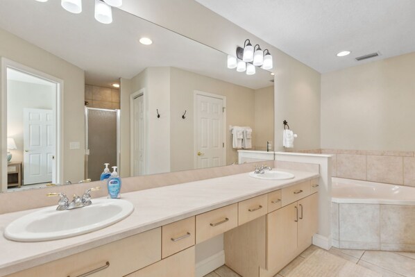 A bathroom with two sinks, a large mirror, and a bathtub. - Amelia Sunrise - Hosted by Moore AI Rentals (Fernandina Beach)