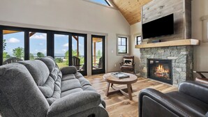 A spacious living room with a stone fireplace, a large flat-screen TV, and a comfortable seating area.