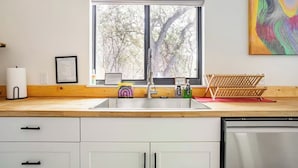 Una cocina con un ventanal grande, un fregadero y un lavavajillas.