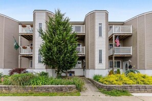 A multi-story residential building with balconies, a central tree, and a well-maintained garden. - Spacious 4 BR Condo with a Garage & Private Decks (Wildwood)