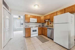 A kitchen with wooden cabinets, a white refrigerator, a microwave, a stove, and a dishwasher. - Spacious 4 BR Condo with a Garage & Private Decks (Wildwood)
